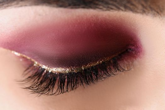 Close-up of pretty makeup on woman face, red autumn colours. Macro shot of bright eye shadow any festive celebration. Mua, beauty, makeup, artist concept