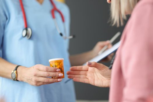 Close-up of female doctor in uniform give container with medication to patient. Qualified specialist advice drug for treatment. Medicine, pharmacy concept