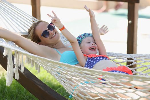 Portrait of smiling woman and child resting on hammock, enjoy life on resort, chilling girls. Summertime, happiness, holiday, family, quality time concept