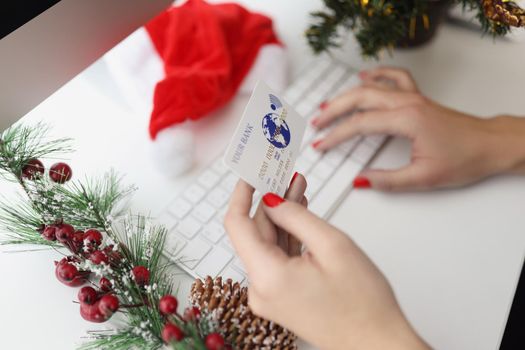 Close-up of woman typing credit card number on keyboard, want to pay online in cashless way. Order presents for new year. Holiday, gift, shopping concept