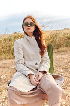 woman sitting on a chair in a field wearing dark glasses harvest. High quality photo