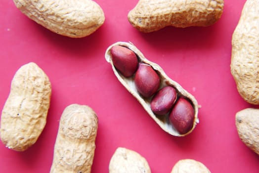 Processed pea nuts on red background close up .