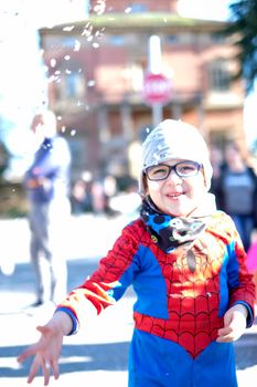 beautiful child with red spider superhero costume playing with confetti. High quality photo