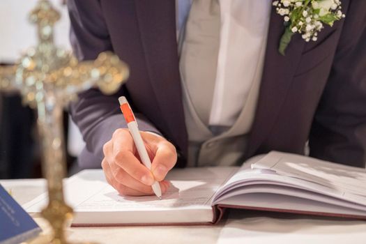 wedding best man groom signing register in catholic wedding. High quality photo