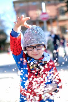 beautiful child with red spider superhero costume playing with confetti. High quality photo