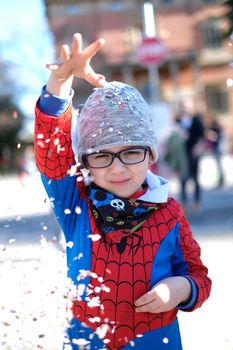 beautiful child with red spider superhero costume playing with confetti. High quality photo