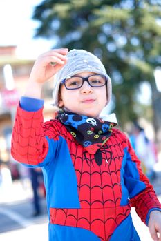 beautiful child with red spider superhero costume playing with confetti. High quality photo