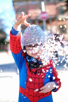 beautiful child with red spider superhero costume playing with confetti. High quality photo