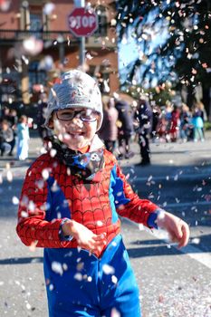 beautiful child with red spider superhero costume playing with confetti. High quality photo