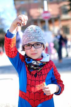 beautiful child with red spider superhero costume playing with confetti. High quality photo