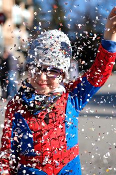 beautiful child with red spider superhero costume playing with confetti. High quality photo