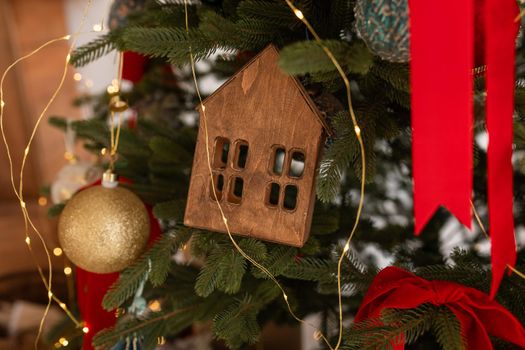 Beautiful decorated christmas tree, red ribbons, balls, wooden house. Merry Christmas and New Year holidays background.