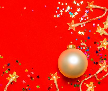 Christmas bauble with star-shaped lights and confetti on red background