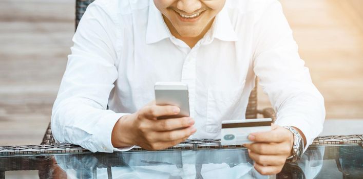 Young Handsome man enjoy shopping online on mobile phone with credit card.