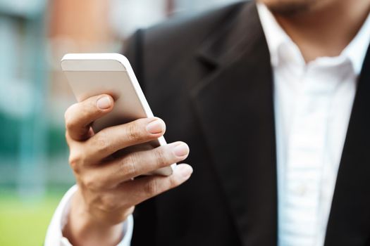 Close-up smart Business man wearing modern black suit and white shirt and texting on mobile smart phone