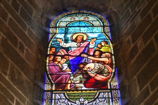 SAINT JUNIEN, FRANCE - DECEMBER 30, 2020: Stained glass windows in a church with Jesus Christ and people asking for healing