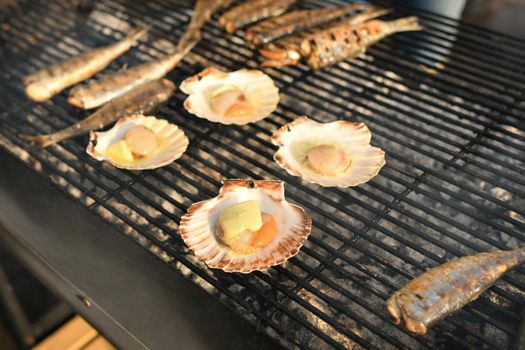 Grilled scallops and herrings on a grill at a market