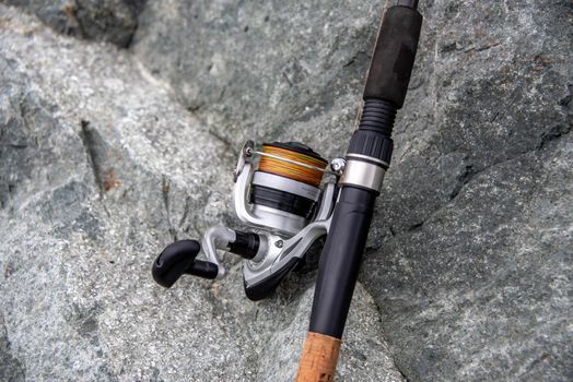 close-up spinning rod for fishing on the background of the stone. Fishing rod and spinning reel for fishing.