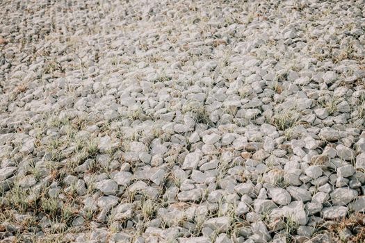 strengthening the slope with stones behind the wire. grey texture. construction. Granite stones behind a metal grate