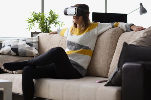 Portrait of female sit on couch wear vr glasses modern device at home and enjoy spare time. Visual effects, fun leisure. Innovation, entertainment concept