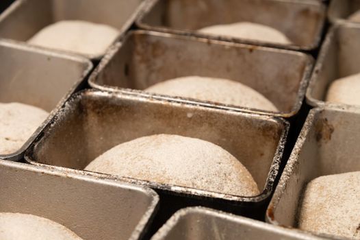 Bread dough in a black metal baking dish on a kitchen countertop. Rye-free rye bread.