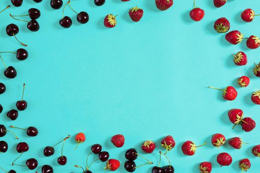 Strawberry and cherries on a blue background. Top view. Copy space. Still life. Flat lay.