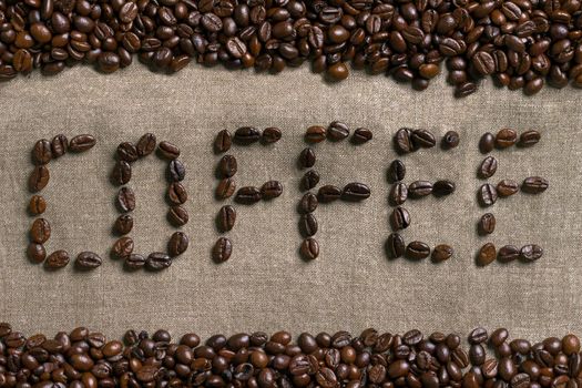 Inscription of coffee with coffee beans on burlap background