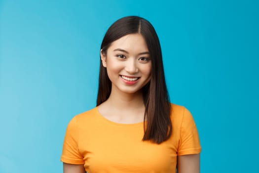 Close-up charming attractive asian girl pure clean skin condition, smiling joyfully look camera upbeat, politely listen, express positive good mood motivated achieve success, stand blue background.