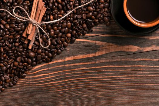 Coffee beans, cinnamon sticks and cup of brewed coffee on rustic wooden table, view from above with space for text. Still life. Mock-up. Flat lay
