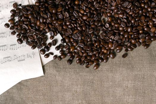 Coffee beans and sheet music on burlap background. Top view. Copy space. Still life. Mock-up. Flat lay