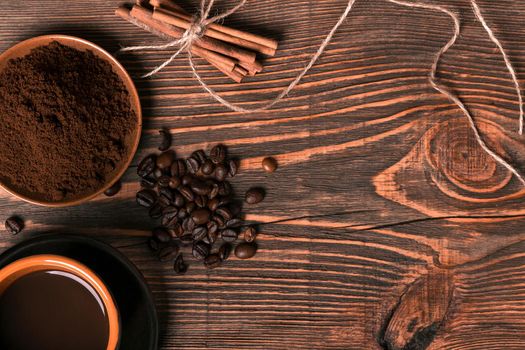 Coffe cup, coffee beans, ground coffee on wooden table background with cinnamon. Top view. Still life. Copy space. Flat lay.