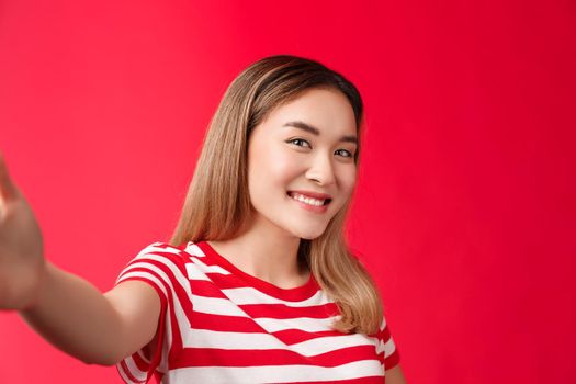Close-up tender feminine silly female student girl taking photos social media extend arm hold smartphone camera make selfie tilt head cute, smiling joyful expression, stand red background.