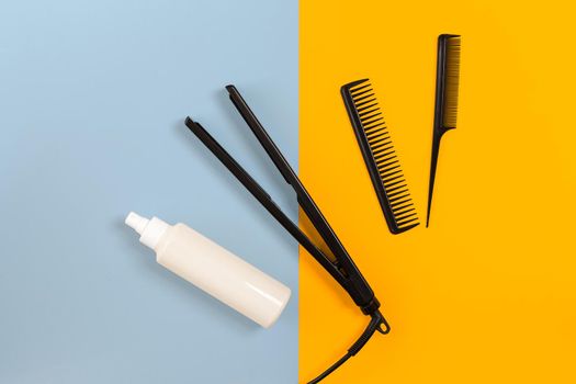 Various hair styling devices on the color blue, yellow paper background, top view. Copy space. Still life. Mock-up. Flat lay