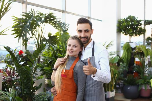 Portrait of young male and female consultants work in flower delivery shop and sale indoor plants. Business, floral design, creative studio, nature concept