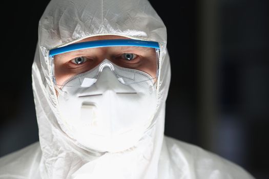 Portrait of male lab worker in protective respirator and white coverall, smart scientist. Male chemist in eyeglasses work on research. Science, lab concept