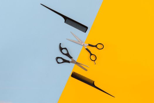 Hairdresser tools on blue and yellow background with copy space, top view, flat lay. Comb, scissors. Still life.