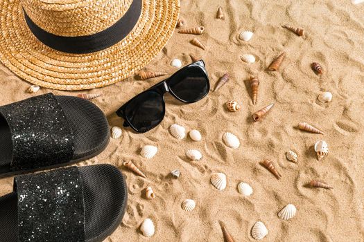 Summer beachwear, flip flops, hat, sunglasses and seashells on sand beach. Top view. Copy space. Still life mockup flat lay