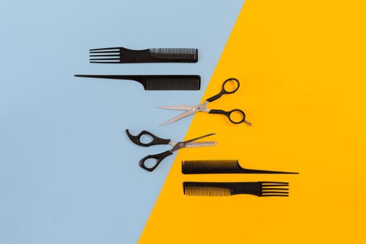 Hairdresser tools on blue and yellow background with copy space, top view, flat lay. Comb, scissors. Still life.