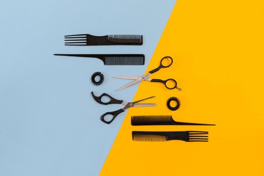 Hairdresser tools on blue and yellow background with copy space, top view, flat lay. Comb, scissors. Still life.