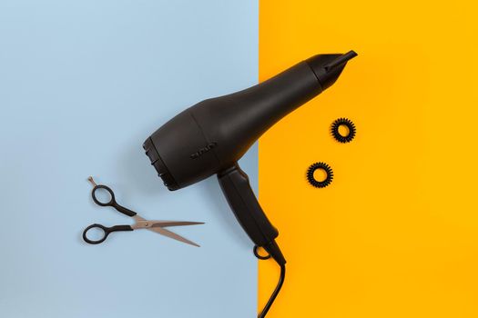 Styling hair with scissors, dryer and tools in barbershop on blue and yellow paper background. Top view. Copy space. Flat lay. Still life. mock-up