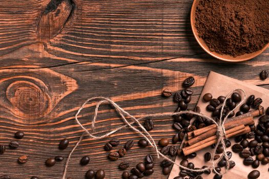 Coffee beans, cinnamon sticks and ground coffee on rustic wooden table, view from above with space for text. Still life. Mock-up. Flat lay