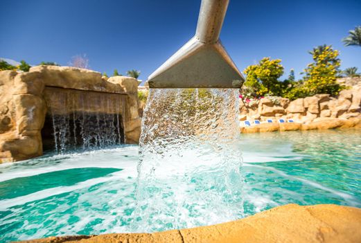 Stream of water out of artificial waterfall in outdoor pool at the luxury hotel in Egypt