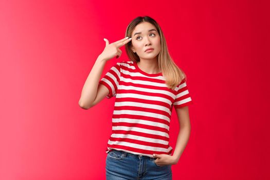 Upset blond asian girl wear striped t-shirt jeans dying boredom sighing look up hold finger gun pistol near temple commit suicide from boring meeting, attend uninteresting party red background.