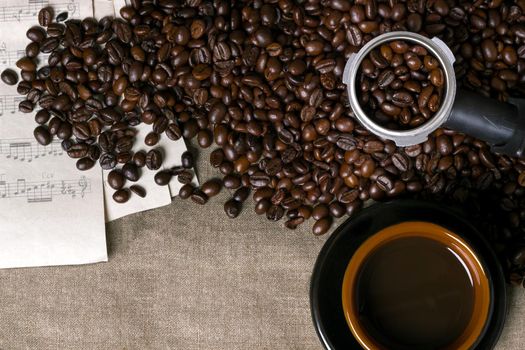 Coffee beans, sheet music and Coffee cup on a burlap background. Top view. Copy space. Still life. Mock-up. Flat lay