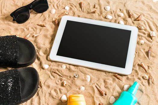 Summer flip-flops, tablet, sunglass and seashell on sand. With place for your text. Top view. Copy space. Still life mockup flat lay
