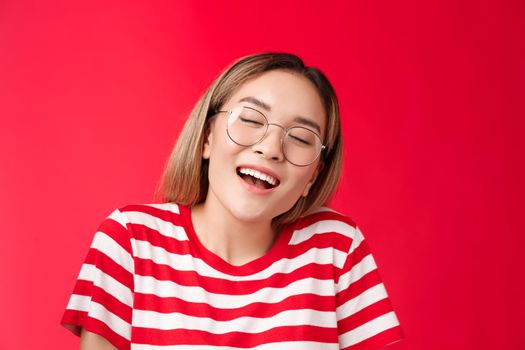 Happy dreamy glad asian girl feel stuffed good after eating favorite sandwich, woman wear glasses close eyes delighted smiling broadly opened mouth fantasizing, dreaming tasty burger.