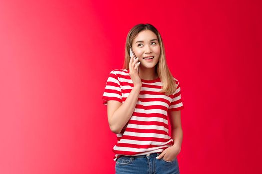 Girl calling friend arranging meeting. Cute modern asian woman hold smartphone near ear look away speaking, smiling delighted have pleasant carefree conversation standing relaxed talking phone.