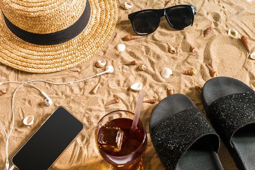 Summer beachwear, flip flops, hat, sunglasses and seashells on sand beach. Top view. Copy space. Still life mockup flat lay