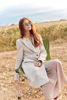 pretty woman in a coat outdoors sitting on a chair autumn season concept. High quality photo