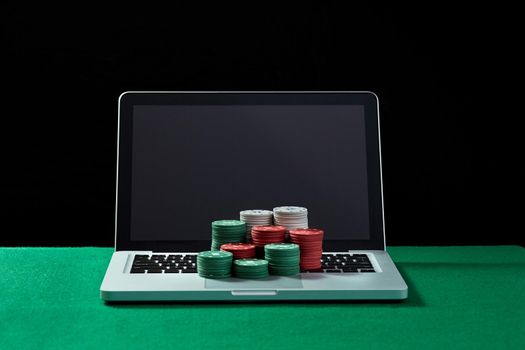 Image of casino chips on a keyboard notebook at green table. Concept for online gambling, poker, virtual casino.